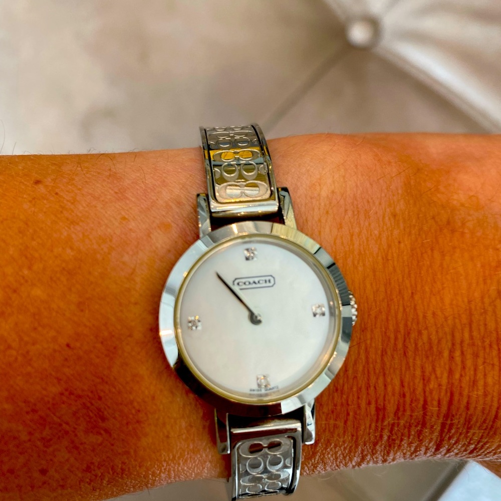 Silver Coach ladies watch. White face. Double “C” band. Safety closure.
